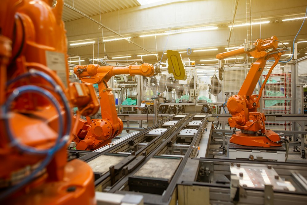 Orange robotic arms on a factory production line